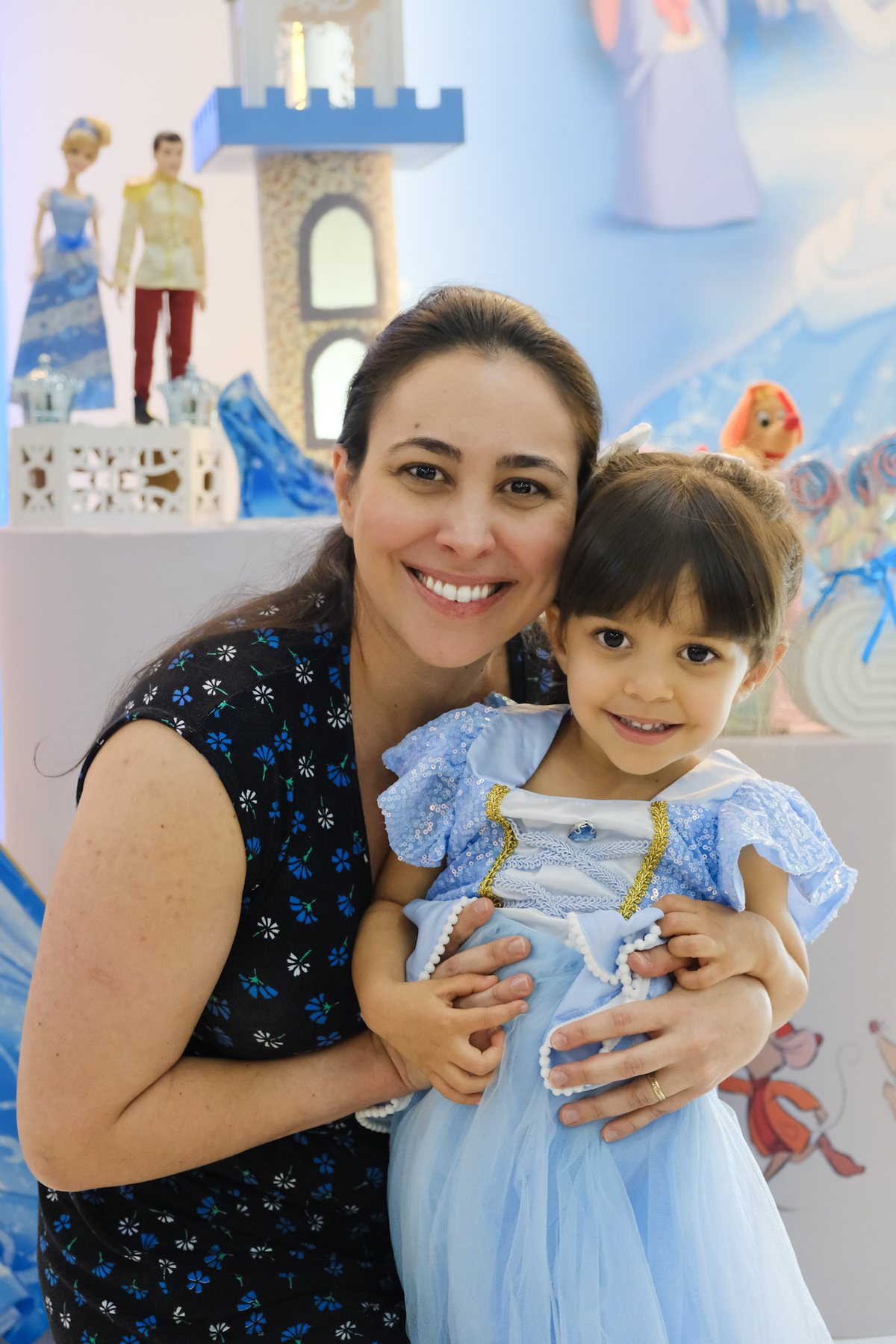 Mãe abraçando a filha de vestido de Cinderela, as duas sorrindo